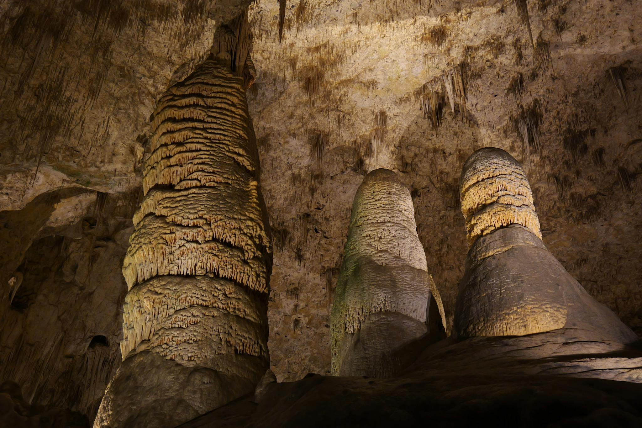 A well-lit cave showcasing stunning stalactite and stalagmite formations.